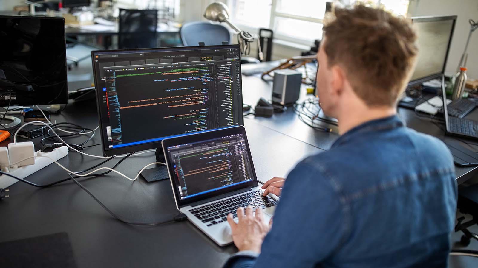 一位男性专业人士坐在办公桌前，正在开发一个新的软件程序.